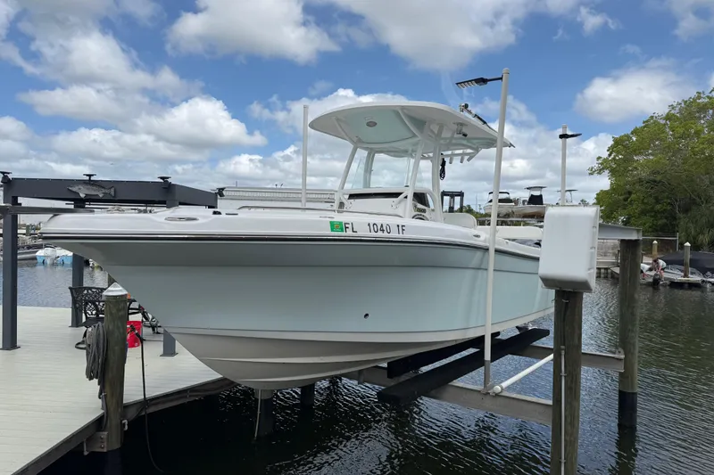 Slide: The Image of 2022 Century 2600 Center Console boat on lift, docked under a cloudy sky. - 7