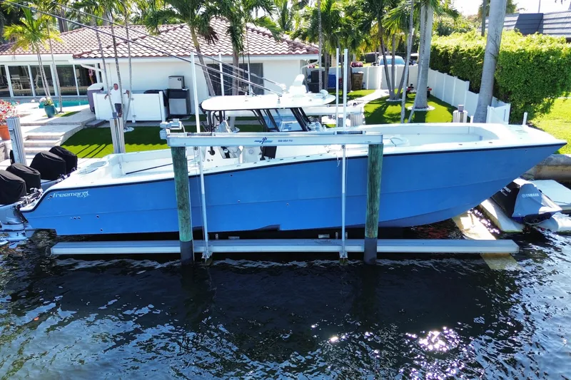 Slide: The Image of Blue 2019 Freeman 42LR boat docked near a waterfront home with palm trees. - 19