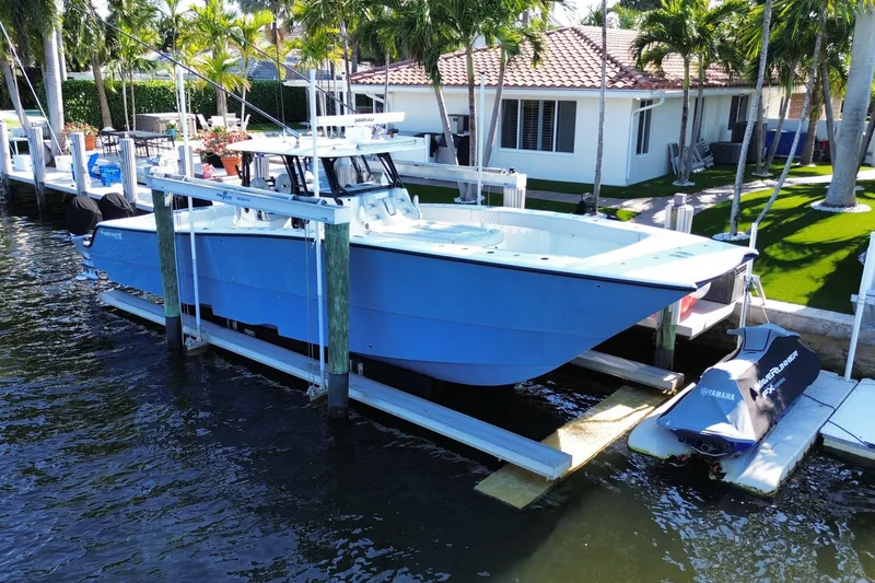 Slide: The Image of Blue 2019 Freeman 42LR boat docked near waterfront home with palm trees. - 20
