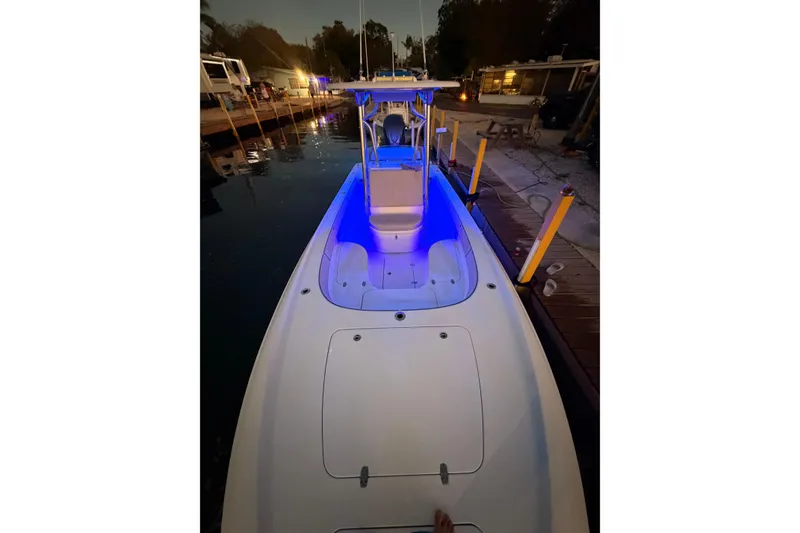 Slide: The Image of 2025 Contender 26 Bay boat docked at night with blue interior lighting. - 12