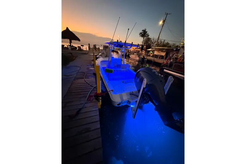 Slide: The Image of 2025 Contender 26 Bay boat docked at sunset with blue underwater lights. - 13