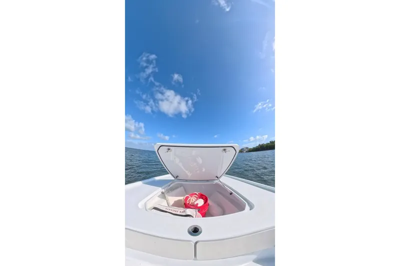 Slide: The Image of 2025 Contender 26 Bay boat on water, open storage compartment, clear blue sky. - 18