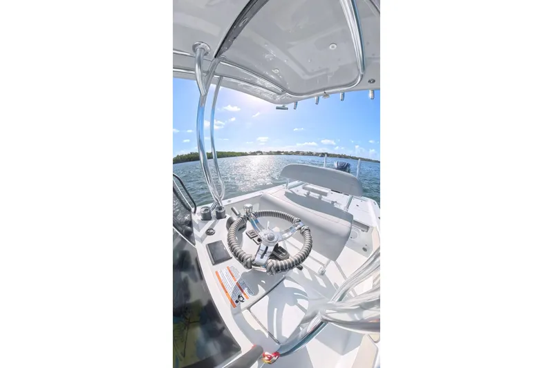 Slide: The Image of 2025 Contender 26 Bay boat interior with steering wheel, overlooking sunny waters. - 21
