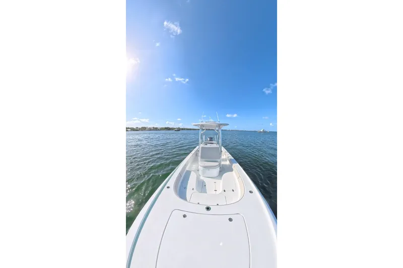 Slide: The Image of 2025 Contender 26 Bay boat on calm water under clear blue sky. - 28