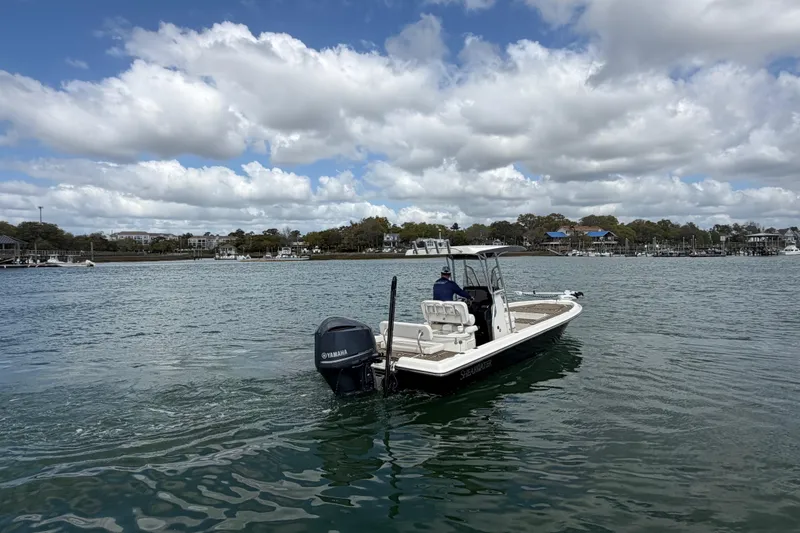 Slide: The Image of 2013 ShearWater 25 LTZ boat cruising on a scenic waterway under cloudy skies. - 10