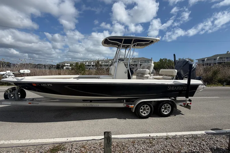 Slide: The Image of 2013 ShearWater 25 LTZ boat on trailer under a partly cloudy sky. - 12