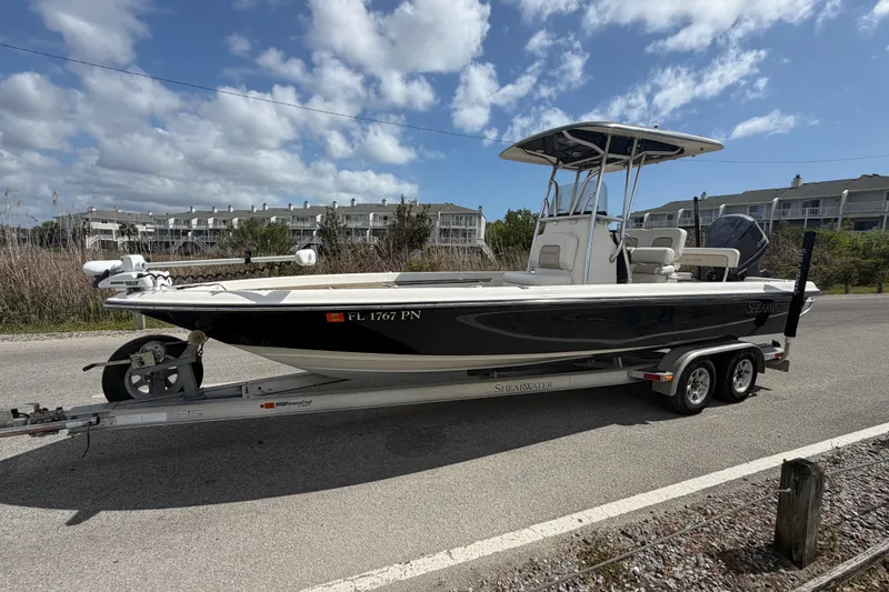 Slide: The Image of 2013 ShearWater 25 LTZ boat on trailer, parked roadside under blue sky. - 13