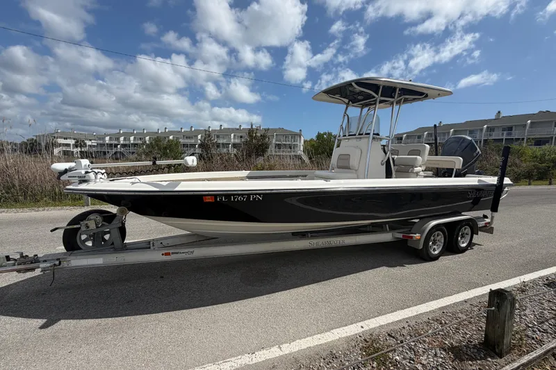 Slide: The Image of 2013 ShearWater 25 LTZ boat on trailer, parked roadside under a cloudy sky. - 14