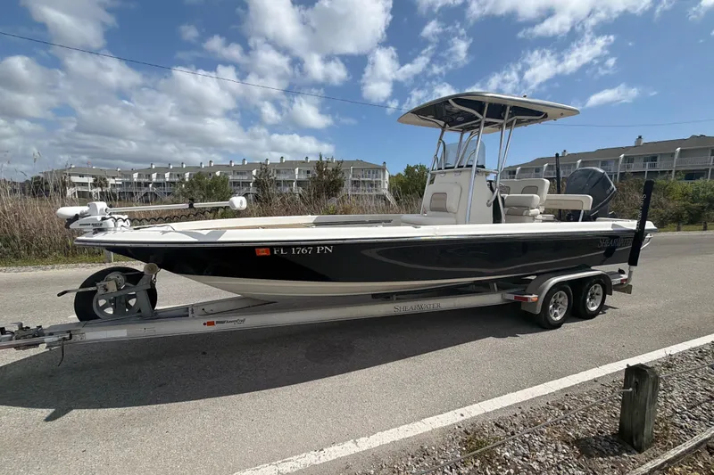 Slide: The Image of 2013 ShearWater 25 LTZ boat on trailer, parked roadside under blue sky. - 15
