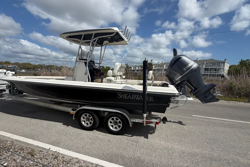 Slide: The Image of 2013 ShearWater 25 LTZ boat on trailer, parked on road under cloudy sky. - 16