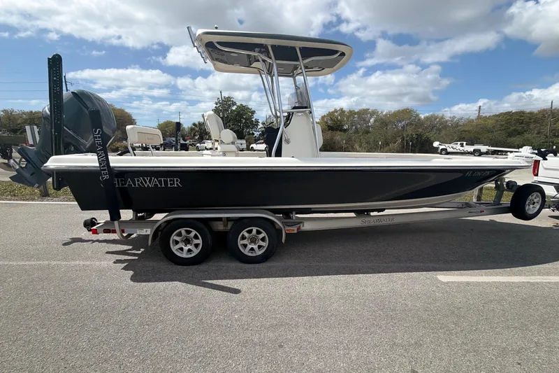 Slide: The Image of 2013 ShearWater 25 LTZ boat on trailer, parked outdoors under a partly cloudy sky. - 23