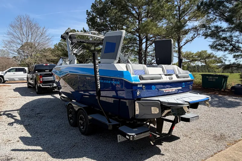 Slide: The Image of 2022 Malibu Wakesetter 25 LSV boat on trailer, parked outdoors near trees. - 7