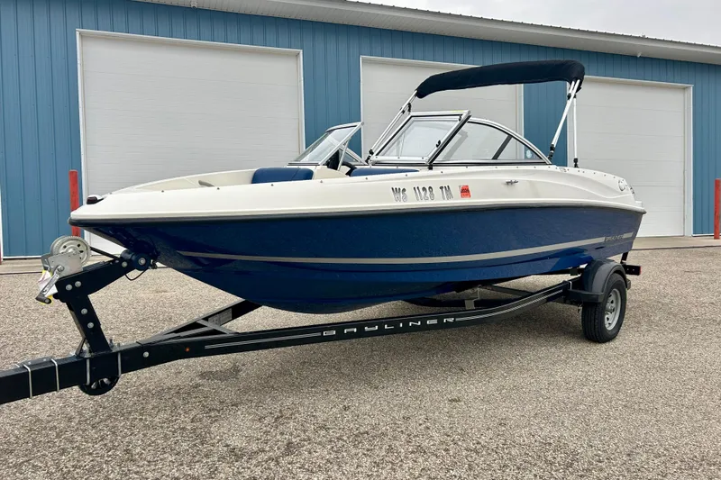 Slide: The Image of 2016 Bayliner 175 Bowrider boat on trailer, parked outside blue building. - 2