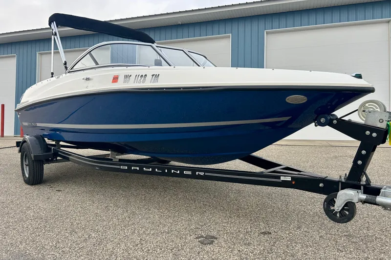 Slide: The Image of 2016 Bayliner 175 Bowrider boat on trailer, parked outside a blue building. - 3