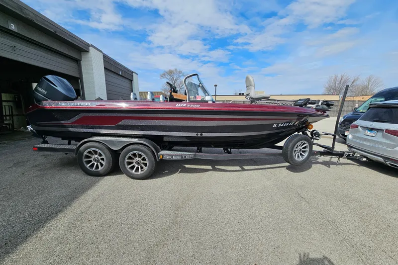 Slide: The Image of 2023 Skeeter WX2200 boat on trailer, parked outdoors under a blue sky. - 6
