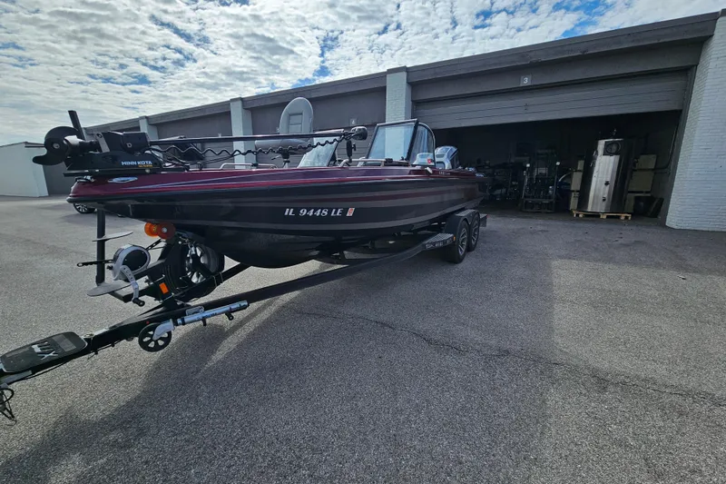 Slide: The Image of 2023 Skeeter WX2200 boat on trailer outside a garage under a cloudy sky. - 8