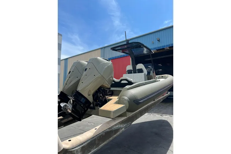 Slide: The Image of 2022 Technohull T9 boat with dual outboard engines, docked near a warehouse. - 11