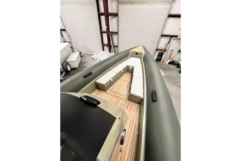 Slide: The Image of 2022 Technohull T9 boat interior with sleek seating and wooden deck in a warehouse. - 14