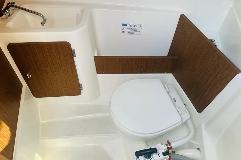 Slide: The Image of Beneteau Antares 7 2020 boat bathroom with sink, toilet, and wooden cabinetry. - 23