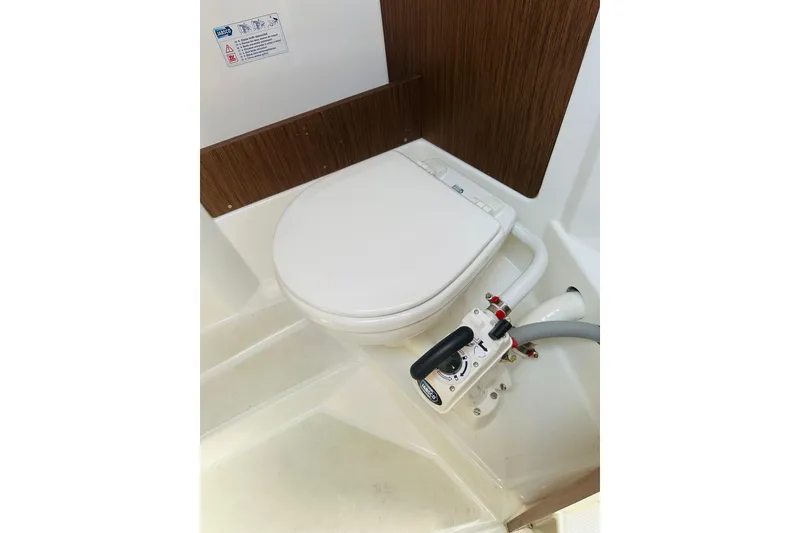 Slide: The Image of Beneteau Antares 7 (2020) boat toilet with manual pump and wooden paneling. - 24