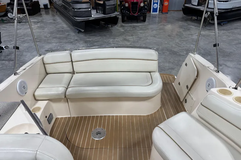 Slide: The Image of 2006 Rinker Fiesta Vee 250 boat interior with beige seating and wood-patterned flooring. - 12