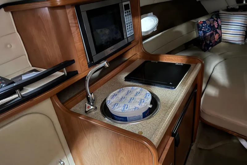 Slide: The Image of 2006 Rinker Fiesta Vee 250 cabin interior with kitchenette and seating area. - 13