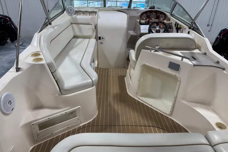 Slide: The Image of 2006 Rinker Fiesta Vee 250 boat interior with seating and helm, featuring beige upholstery. - 9