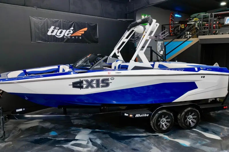 The Image of 2023 Axis A225 boat in showroom, blue and white design, on trailer. - 1