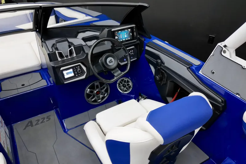 Slide: The Image of 2023 Axis A225 boat interior with blue and white seating, modern dashboard, and steering wheel. - 10