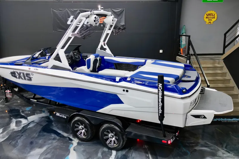 Slide: The Image of 2023 Axis A225 boat in showroom, blue and white design, on trailer. - 12