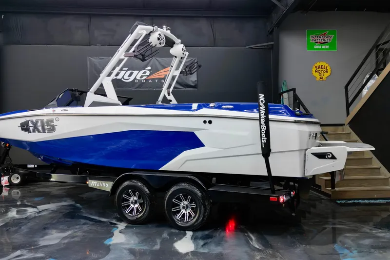 Slide: The Image of 2023 Axis A225 boat in showroom, blue and white design, on trailer. - 3