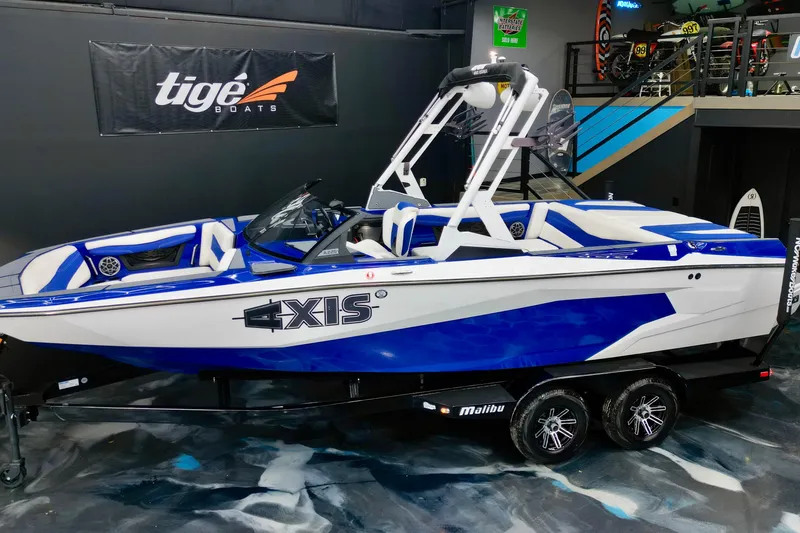 Slide: The Image of 2023 Axis A225 boat in showroom, blue and white design, displayed on trailer. - 4