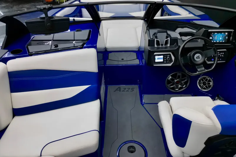 Slide: The Image of 2023 Axis A225 boat interior with blue and white seating, modern dashboard, and steering wheel. - 9