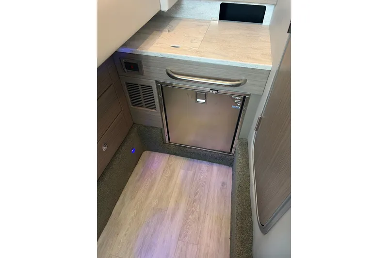 Slide: The Image of 2019 Formula 350 Crossover Bowrider I/O interior with compact kitchenette and stainless steel fridge. - 15