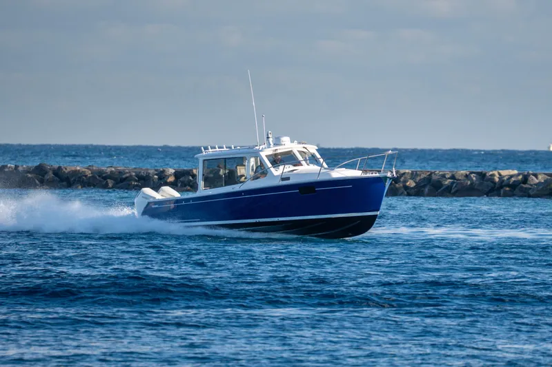 Slide: The Image of 2026 MJM 38RS boat cruising on open water near rocky shoreline. - 18