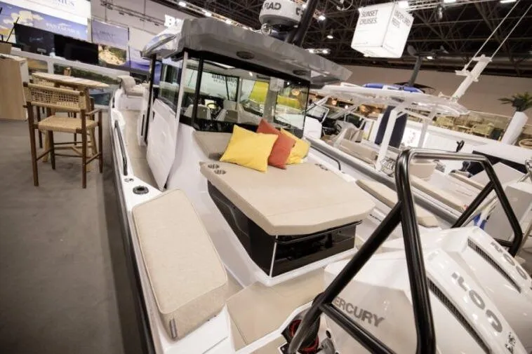 Slide: The Image of 2027 Axopar 29 XC Cross Cabin boat with cushioned seating at a boat show. - 3