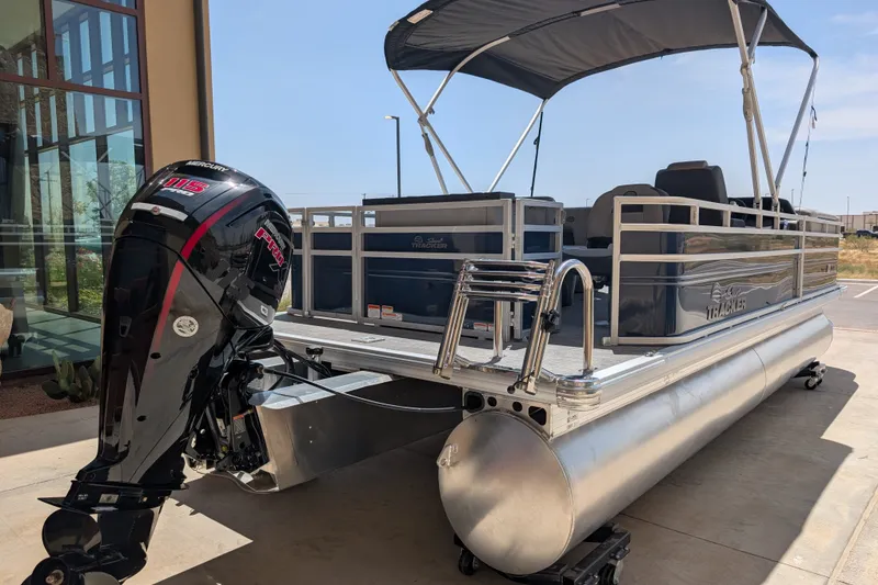 Slide: The Image of 2026 Sun Tracker SportFish 22 DLX pontoon boat with Mercury 115 engine, docked outdoors. - 94