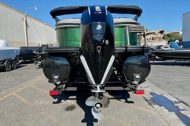 Slide: The Image of 2026 Regency 230 DL pontoon boat with powerful outboard motor, parked outdoors. - 12