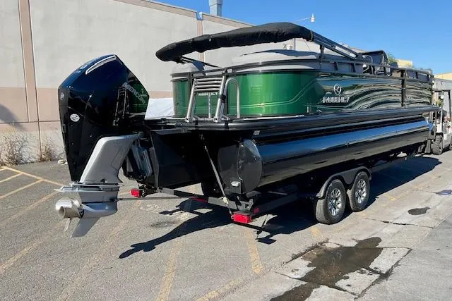 Slide: The Image of 2026 Regency 230 DL pontoon boat on trailer, featuring a sleek green and black design. - 13