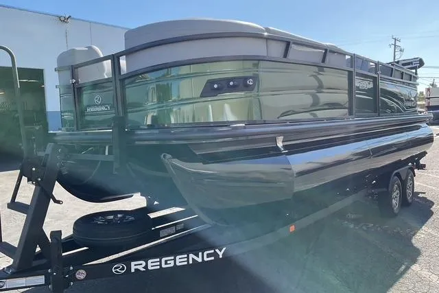 Slide: The Image of 2026 Regency 230 DL pontoon boat on trailer, parked outdoors. - 2