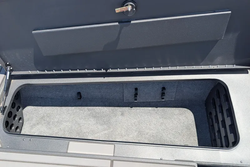 Slide: The Image of Open storage compartment in 2026 Tracker Savage 215 boat, featuring carpeted interior and secure latch. - 15