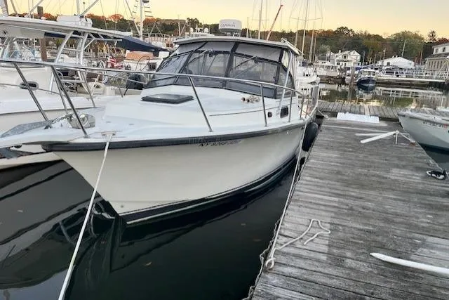 The Image of 1989 Rampage 28 Sportsman boat docked at a marina, surrounded by other vessels. - 0