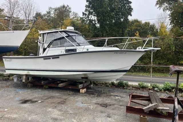 Slide: The Image of 1989 Rampage 28 Sportsman boat on dry dock, surrounded by trees and fencing. - 2