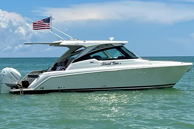 The Image of 2020 Tiara Sport 34 LX boat on water with American flag, clear sky background. - 0