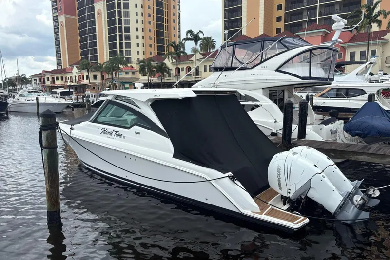 Slide: The Image of 2020 Tiara Sport 34 LX boat docked at marina with luxury buildings in background. - 2