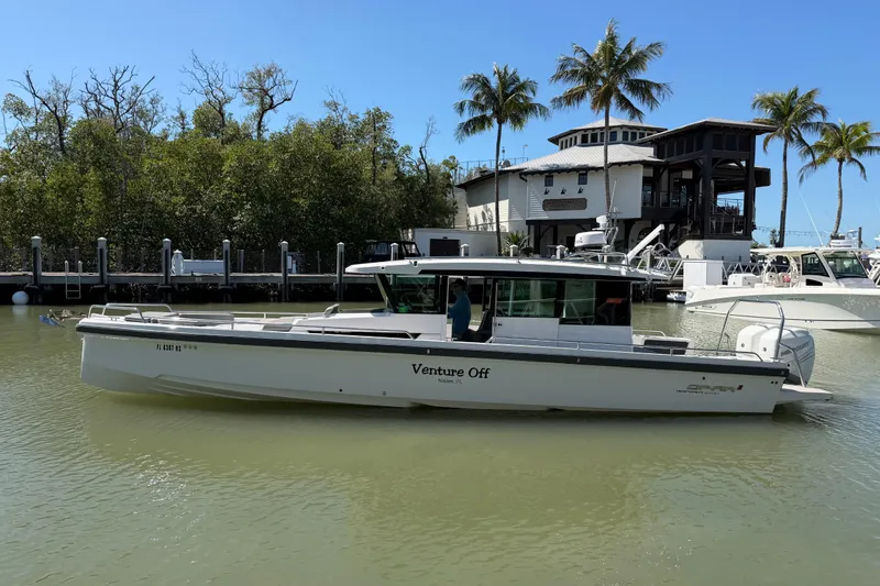 Slide: The Image of 2018 Axopar 37 Cabin boat docked near a waterfront house with palm trees. - 2