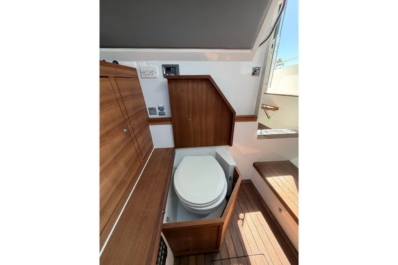 Slide: The Image of 2018 Axopar 37 Cabin interior with wooden cabinetry and compact marine toilet. - 23