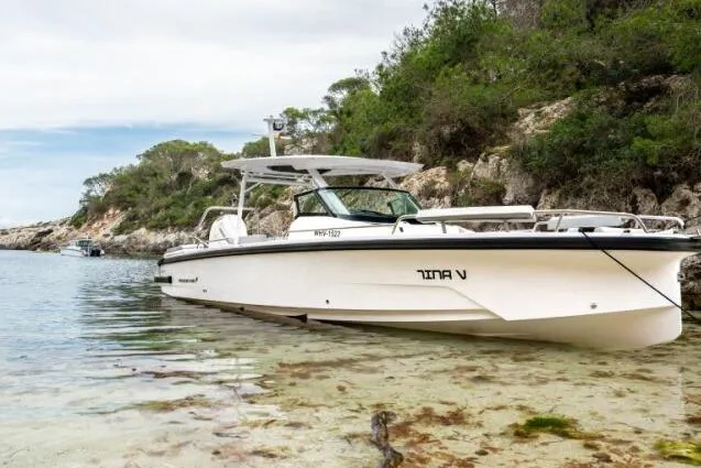 The Image of 2027 Axopar 29 Sun-Top boat docked in a scenic, rocky shoreline setting. - 0