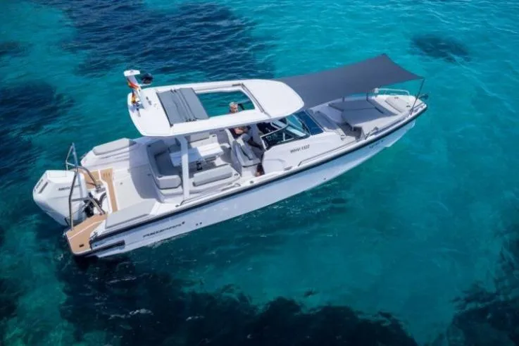 Slide: The Image of 2027 Axopar 29 Sun-Top boat cruising on clear blue water. - 2