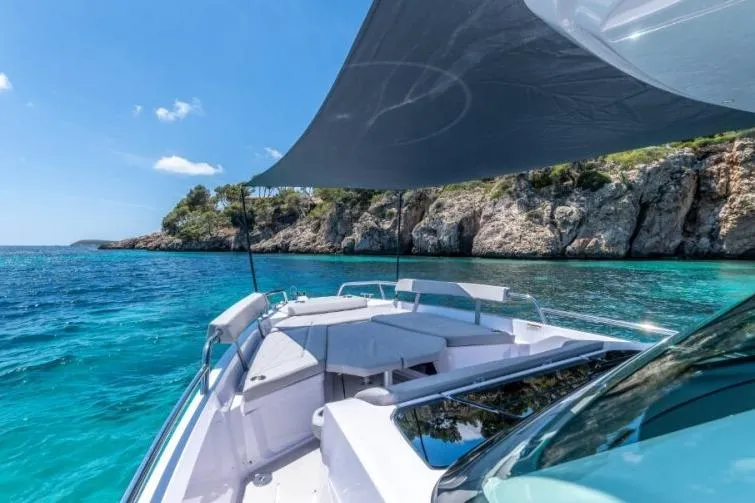 Slide: The Image of 2027 Axopar 29 Sun-Top boat cruising in clear turquoise waters near rocky coastline. - 4